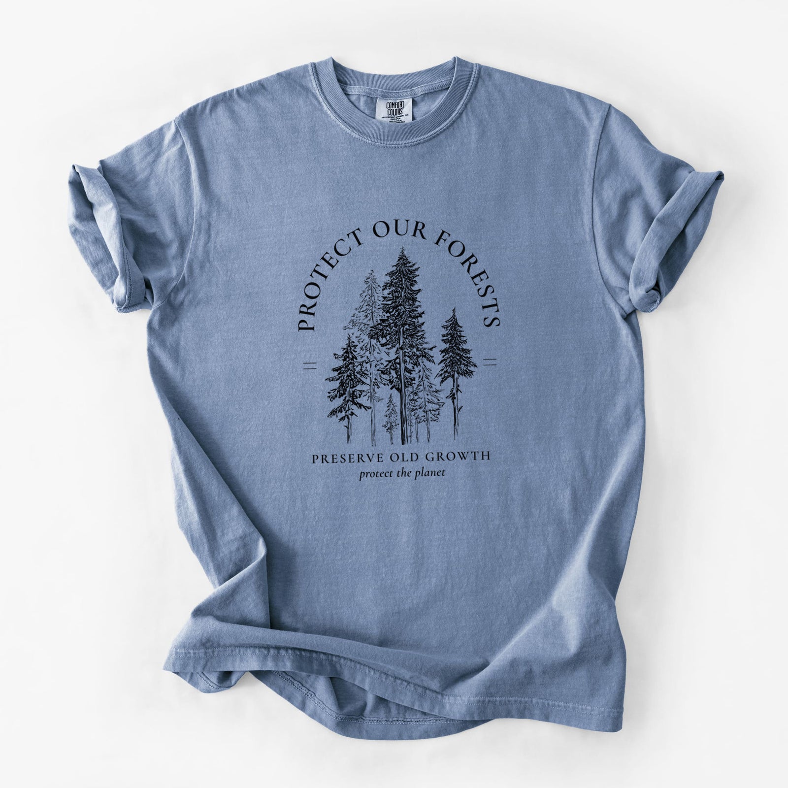 Blue jean Comfort Colors t-shirt laid flat, printed with a black ink illustration of a stand of tall pine trees, framed by the words Protect Our Forests, Preserve Old Growth.