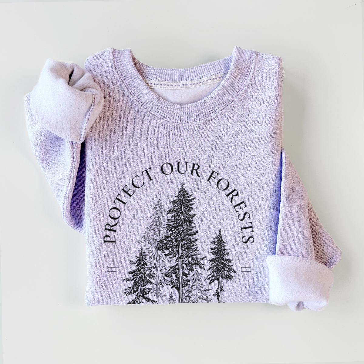 Ice purple knit sweatshirt printed with a black ink illustration of a stand of tall pine trees, framed by the words Protect Our Forests, Preserve Old Growth, styled flat.