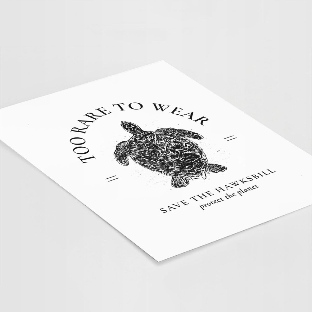 Art print of a black ink hawksbill sea turtle framed by the words Too Rare to Wear, Save the Hawksbill, lying at an angle on a white surface.