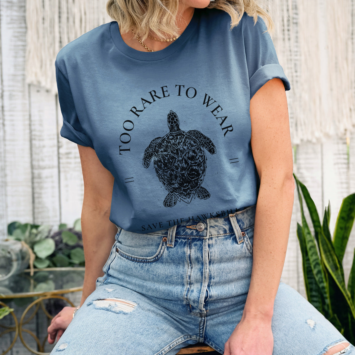Woman wearing a steel blue lightweight cotton t-shirt printed with a black ink hawksbill sea turtle framed by the words Too Rare to Wear, Save the Hawksbill.