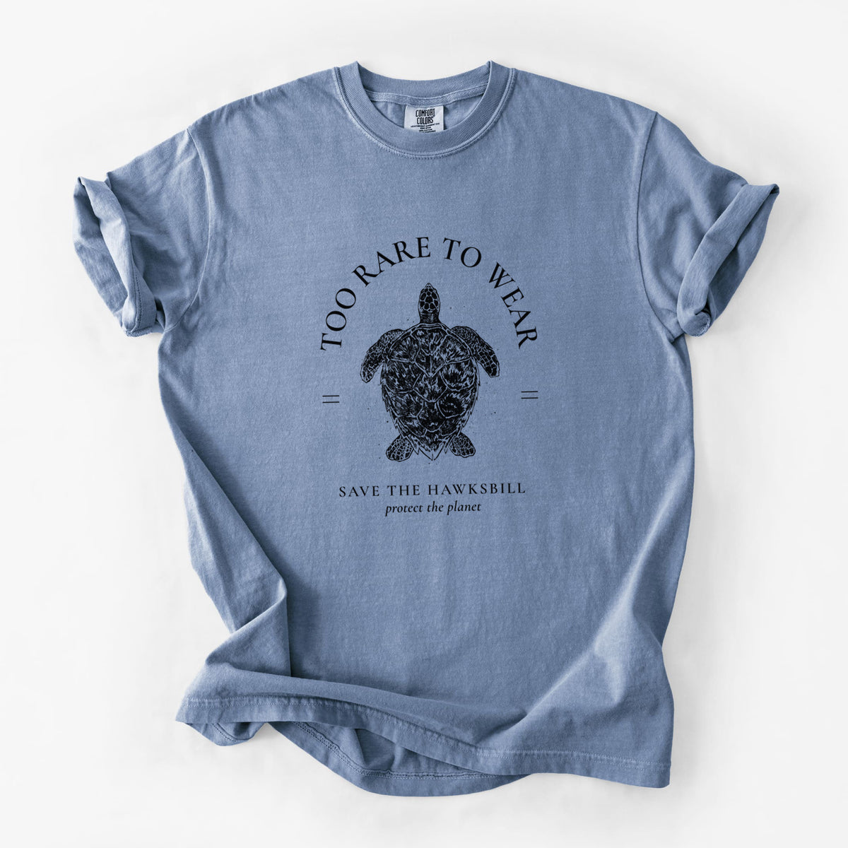 Blue jean Comfort Colors t-shirt laid flat, printed with a black ink hawksbill sea turtle framed by the words Too Rare to Wear, Save the Hawksbill.