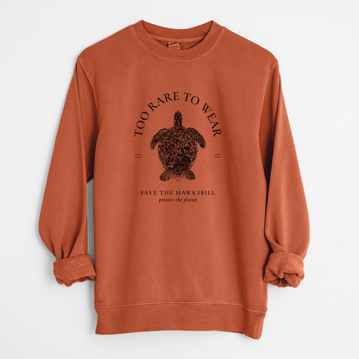 Amber orange pigment dyed crewneck sweatshirt laid flat with the sleeves rolled, printed with a black ink hawksbill sea turtle framed by the words Too Rare to Wear, Save the Hawksbill.