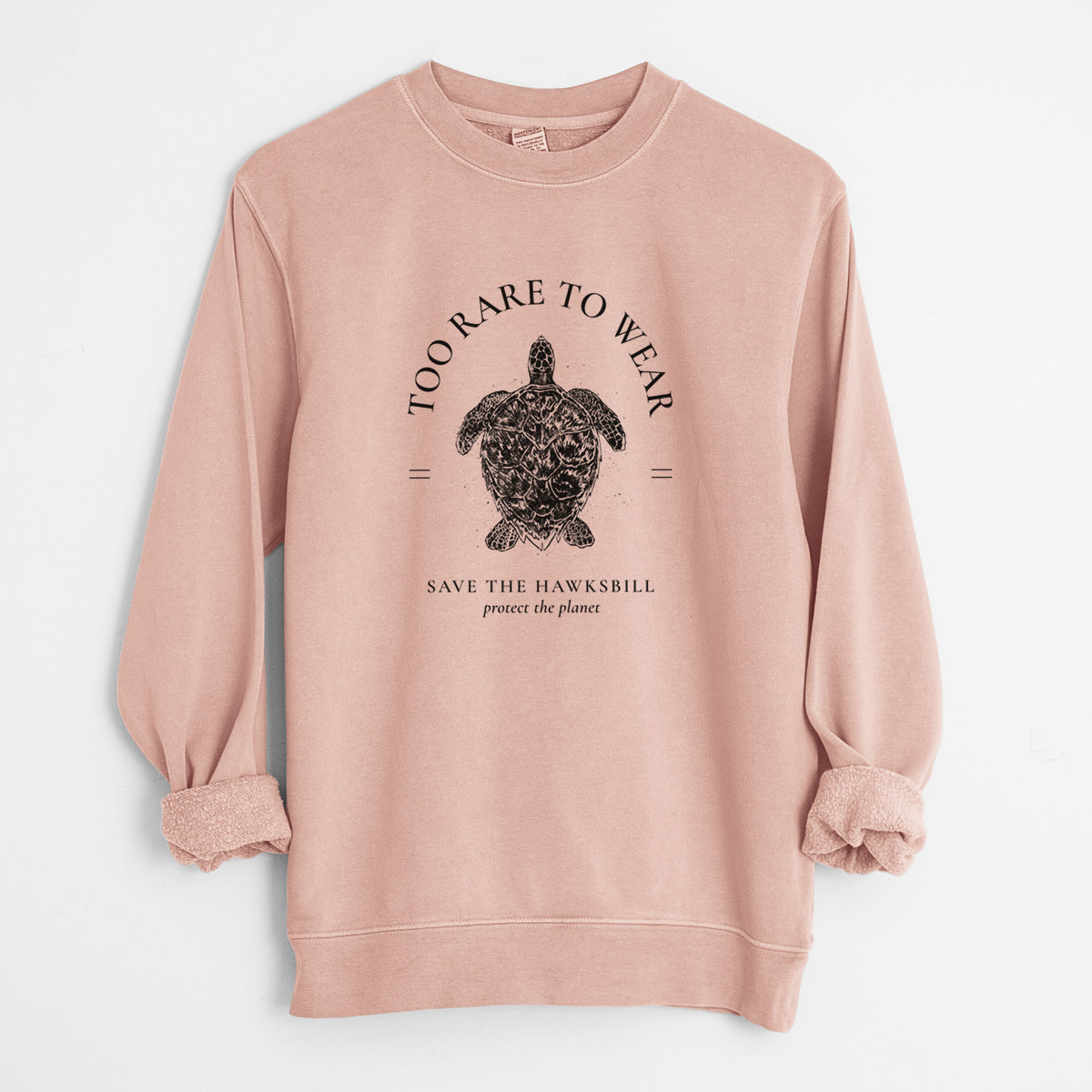 Dusty pink pigment dyed crewneck sweatshirt laid flat with the sleeves rolled, printed with a black ink hawksbill sea turtle framed by the words Too Rare to Wear, Save the Hawksbill.