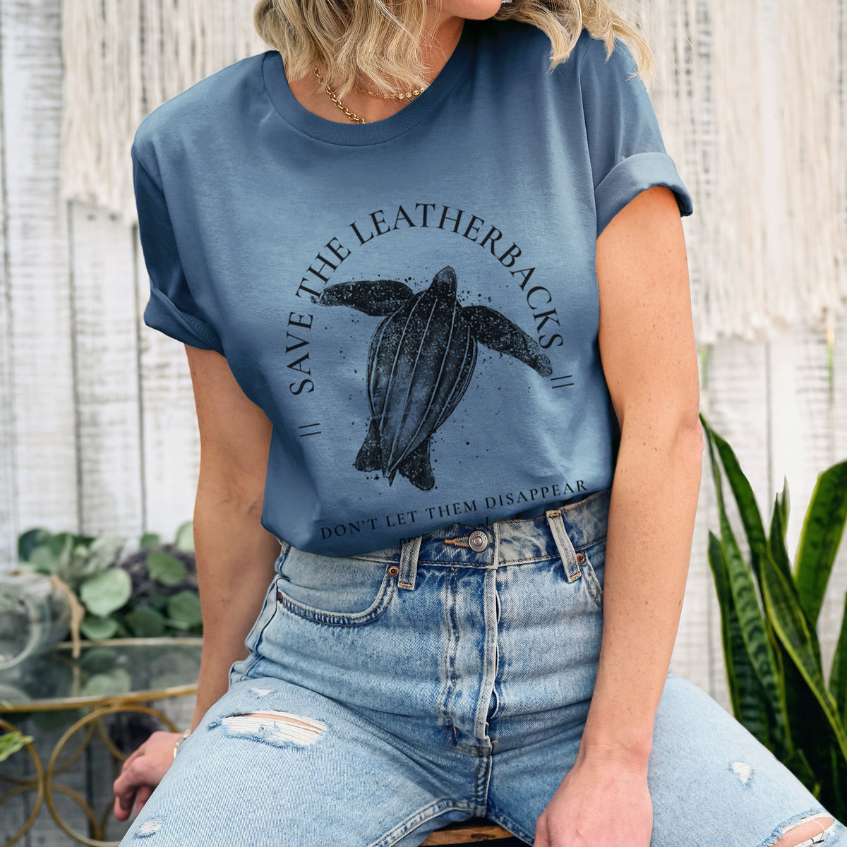 Woman wearing a steel blue lightweight cotton t-shirt printed with a black ink leatherback sea turtle framed by the words Save the Leatherbacks, Don't Let Them Disappear.