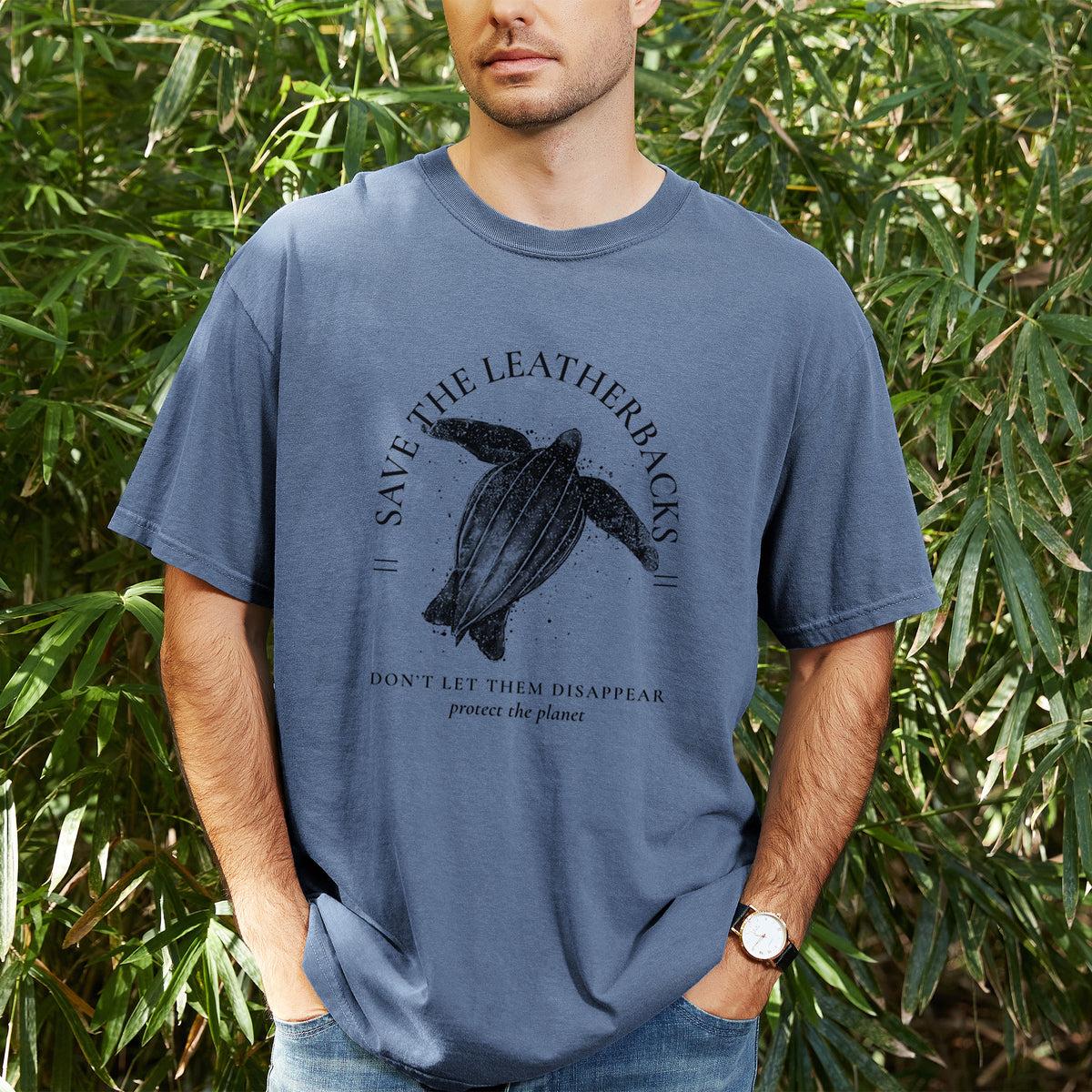 Man wearing a Comfort Colors t-shirt printed with a black ink leatherback sea turtle framed by the words Save the Leatherbacks, Don't Let Them Disappear, outdoors.