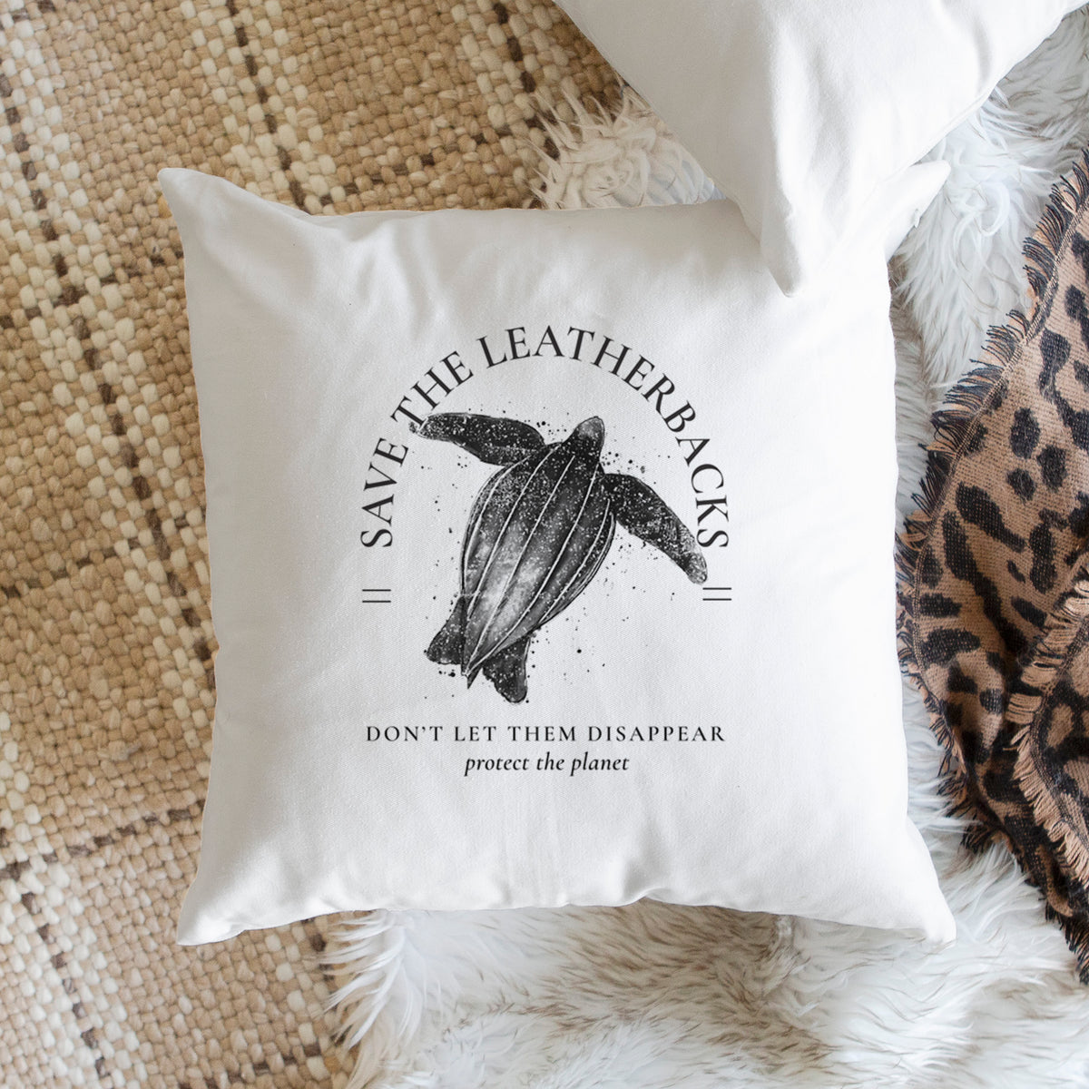 White pillow cover printed with a black ink leatherback sea turtle framed by the words Save the Leatherbacks, Don't Let Them Disappear, on a woven chair.