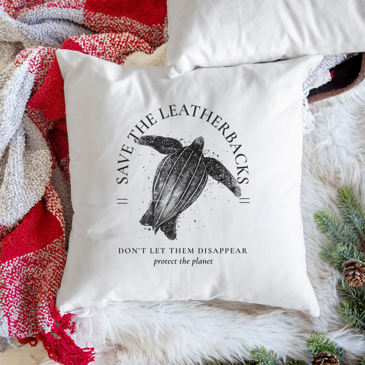 White pillow cover printed with a black ink leatherback sea turtle framed by the words Save the Leatherbacks, Don't Let Them Disappear, on a woven chair.
