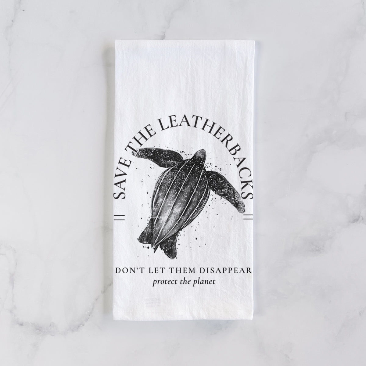 White cotton tea towel laid flat on marble, printed with a black ink leatherback sea turtle framed by the words Save the Leatherbacks, Don't Let Them Disappear.