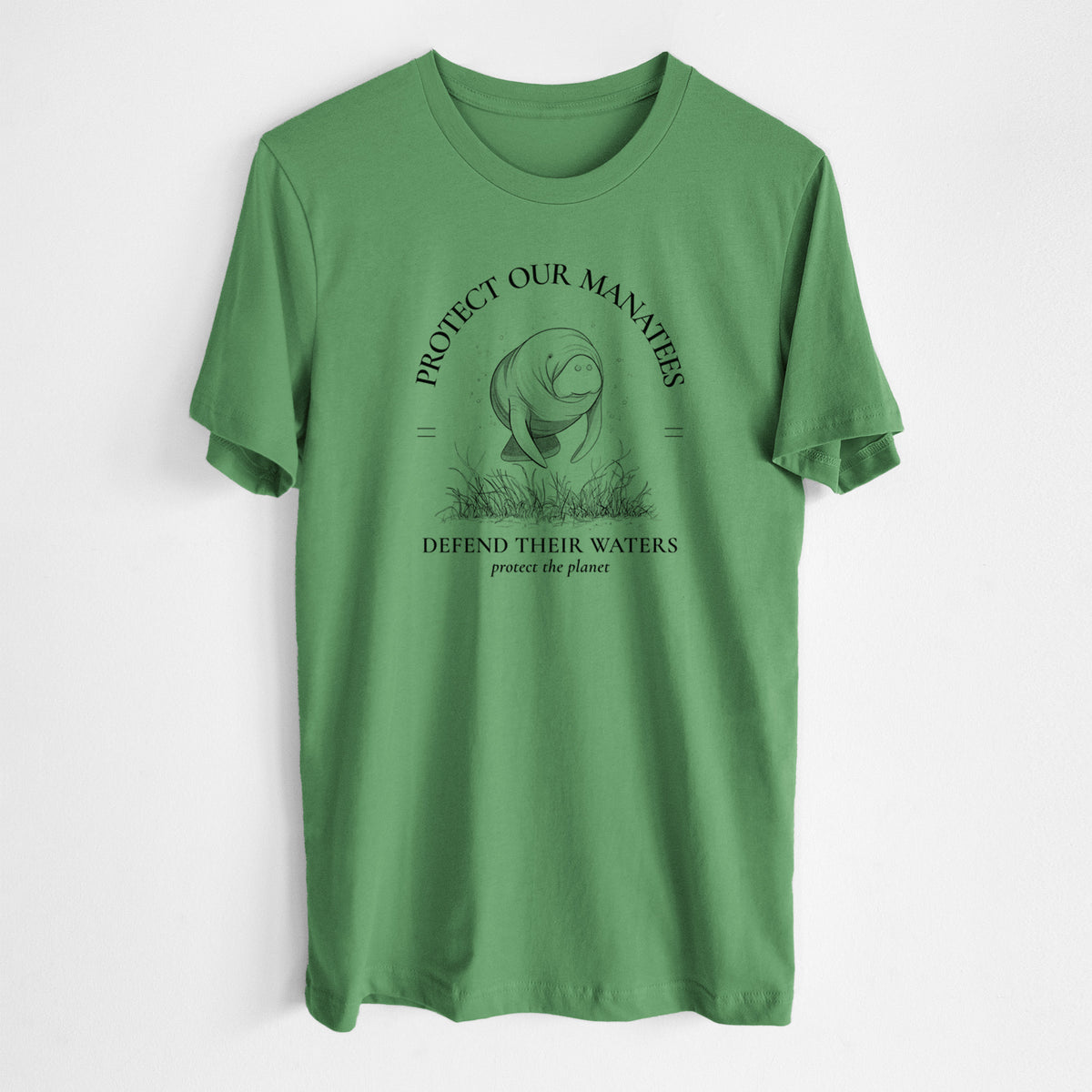 Leaf green lightweight cotton t-shirt laid flat, printed with a black ink illustration of a manatee among seagrass, framed by the words Protect Our Manatees, Defend Their Waters, Protect the Planet.