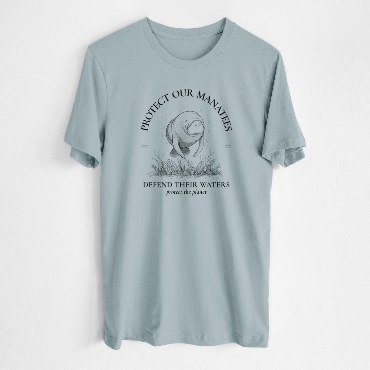 Vintage denim lightweight cotton t-shirt laid flat, printed with a black ink illustration of a manatee among seagrass, framed by the words Protect Our Manatees, Defend Their Waters, Protect the Planet.