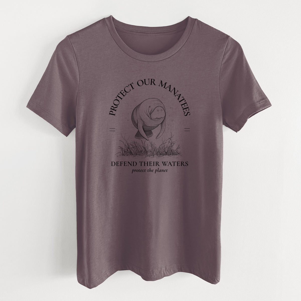 Purple storm women's relaxed fit cotton t-shirt laid flat, printed with a black ink illustration of a manatee among seagrass, framed by the words Protect Our Manatees, Defend Their Waters, Protect the Planet.