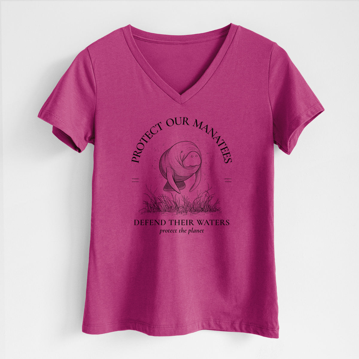 Berry pink women's relaxed fit cotton V-neck t-shirt laid flat, printed with a black ink illustration of a manatee among seagrass, framed by the words Protect Our Manatees, Defend Their Waters, Protect the Planet.