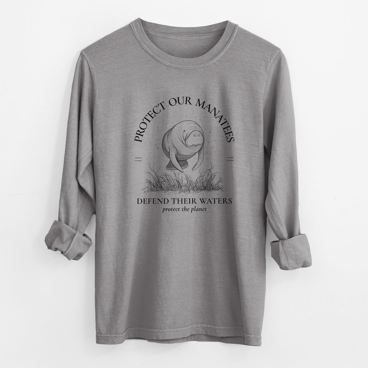 Grey Comfort Colors long sleeve shirt laid flat with the cuffs rolled, printed with a black ink illustration of a manatee among seagrass, framed by the words Protect Our Manatees, Defend Their Waters, Protect the Planet.