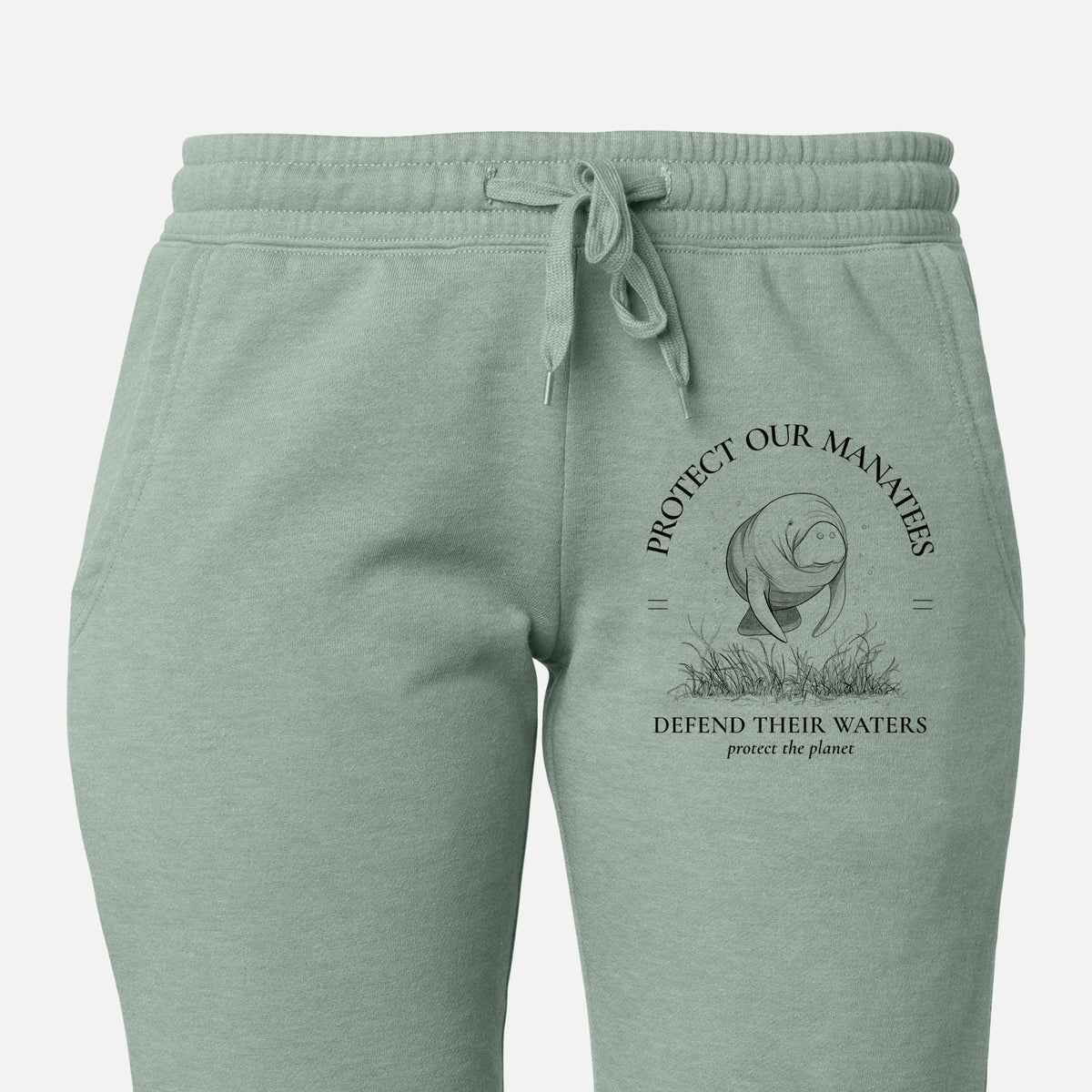 Front of sage green Cali Wave sweatpants, printed with a black ink illustration of a manatee among seagrass, framed by the words Protect Our Manatees, Defend Their Waters, Protect the Planet on the leg.