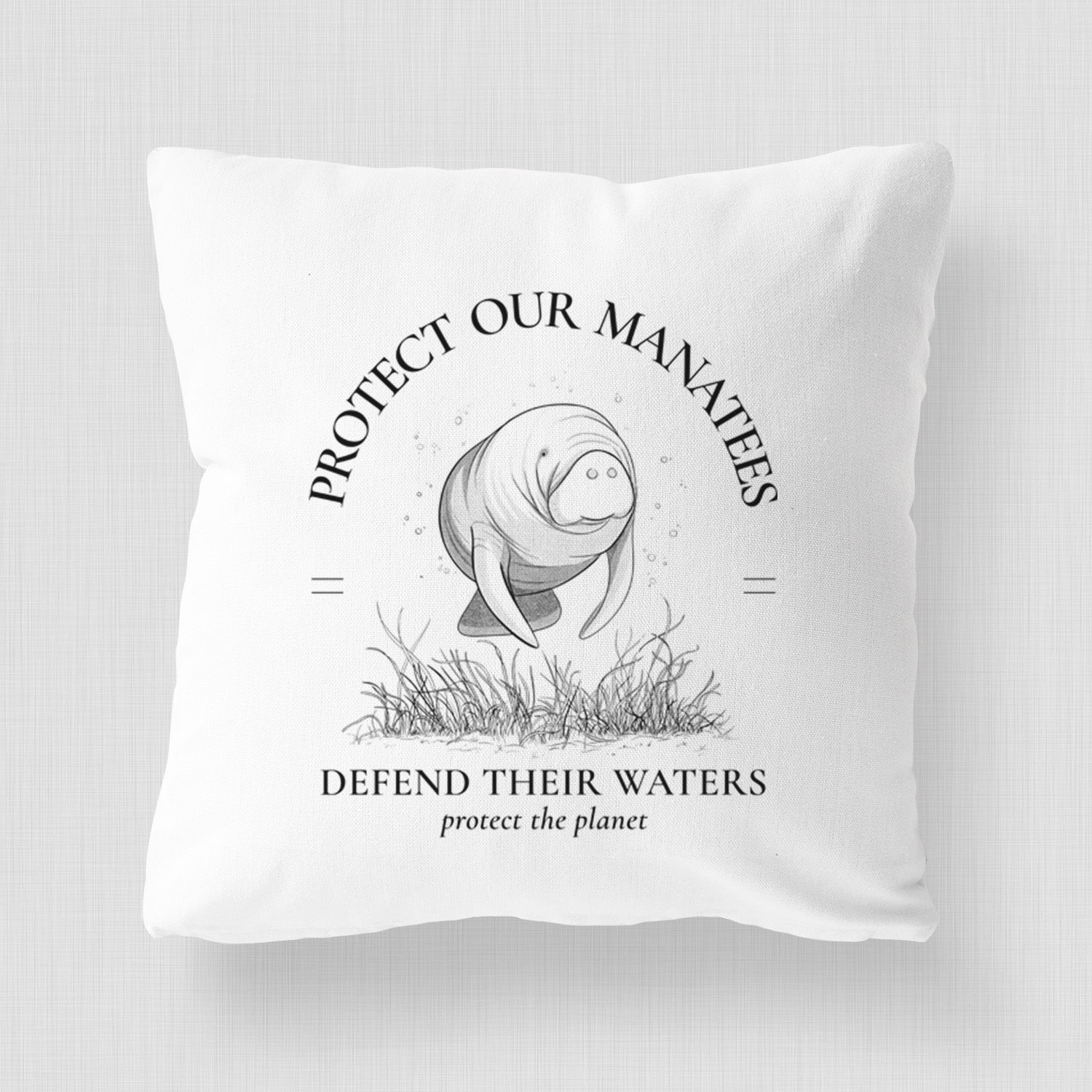 White pillow cover printed with a black ink illustration of a manatee among seagrass, framed by the words Protect Our Manatees, Defend Their Waters, Protect the Planet, on a bench beside plants.