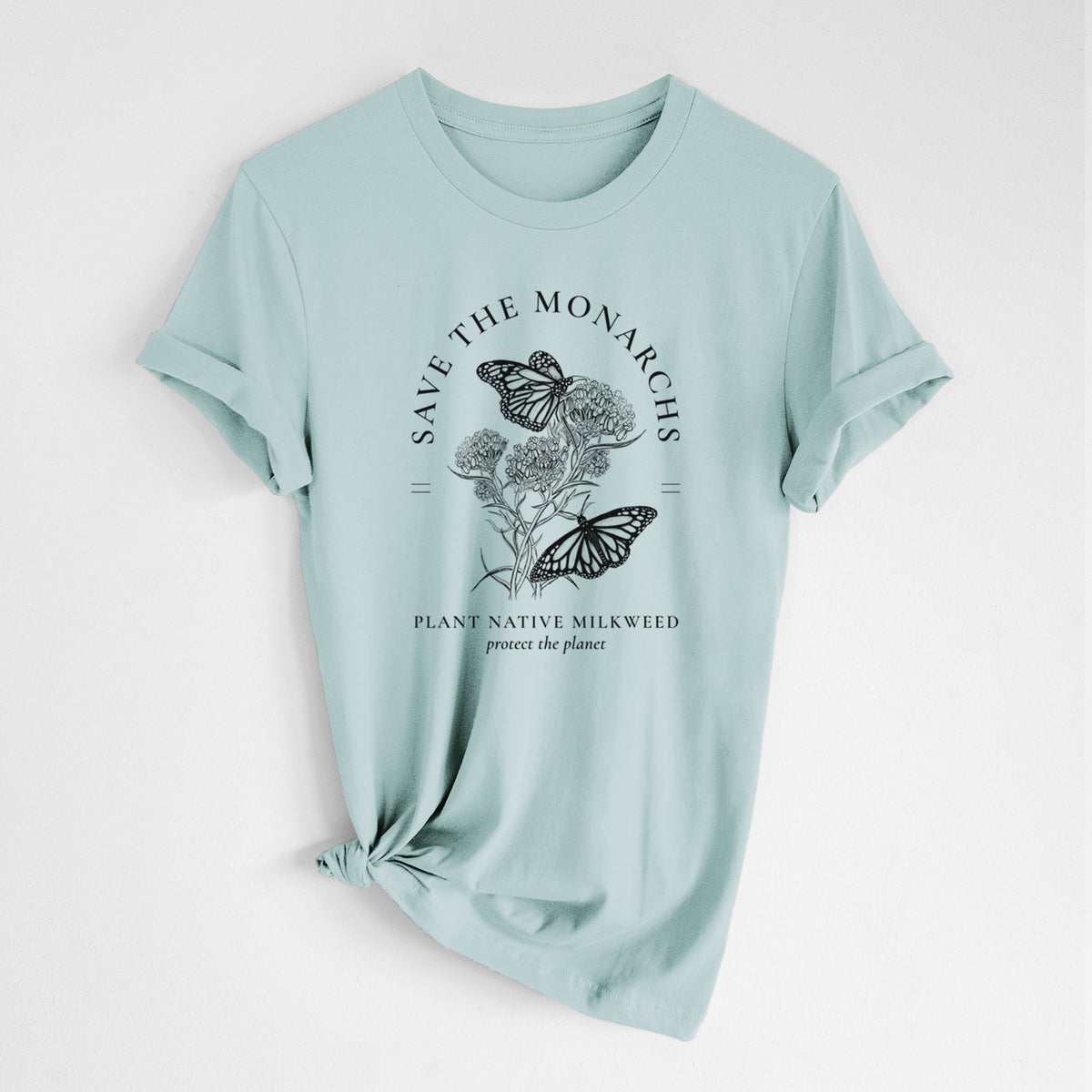 Dusty blue lightweight cotton t-shirt laid flat with the sleeves rolled, printed with black ink monarch butterflies on milkweed flowers, framed by the words Save the Monarchs, Plant Native Milkweed.