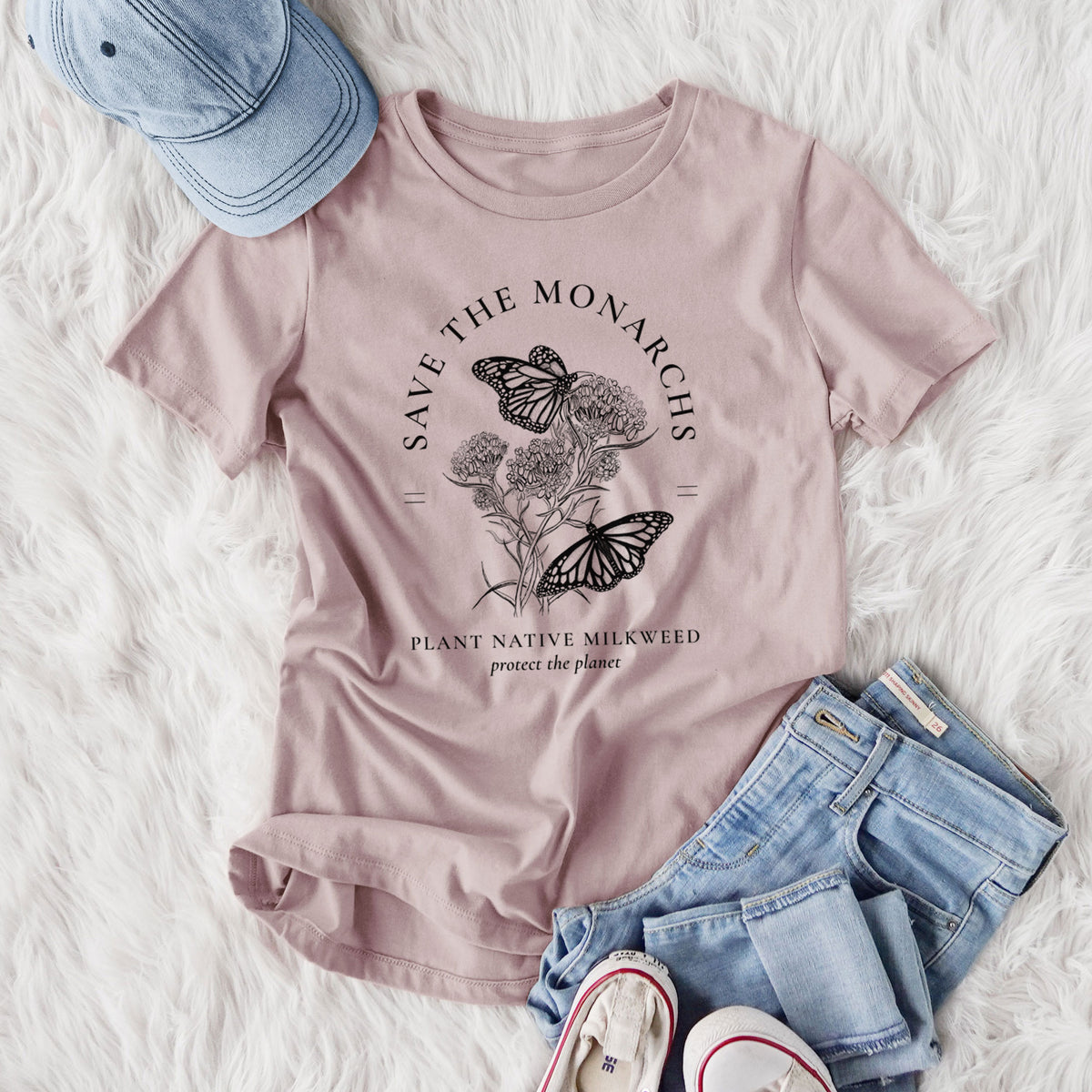 Women's relaxed fit cotton t-shirt printed with black ink monarch butterflies on milkweed flowers, framed by the words Save the Monarchs, Plant Native Milkweed, styled flat on a white faux fur rug with jeans.