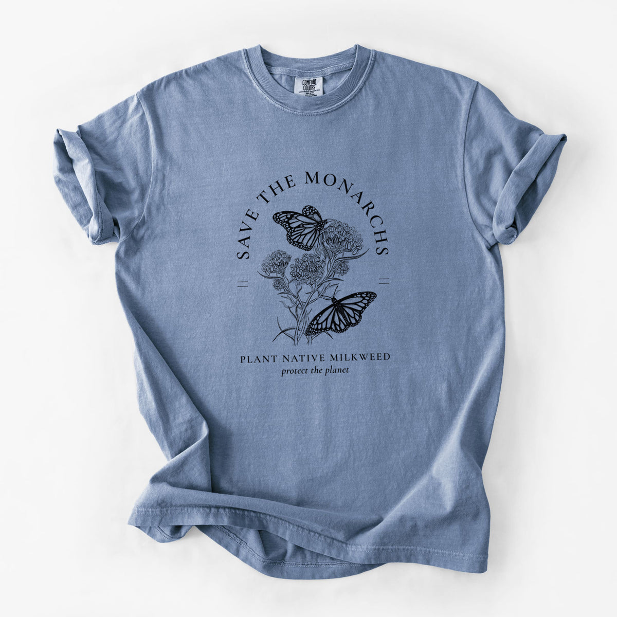 Blue jean Comfort Colors t-shirt laid flat, printed with black ink monarch butterflies on milkweed flowers, framed by the words Save the Monarchs, Plant Native Milkweed.