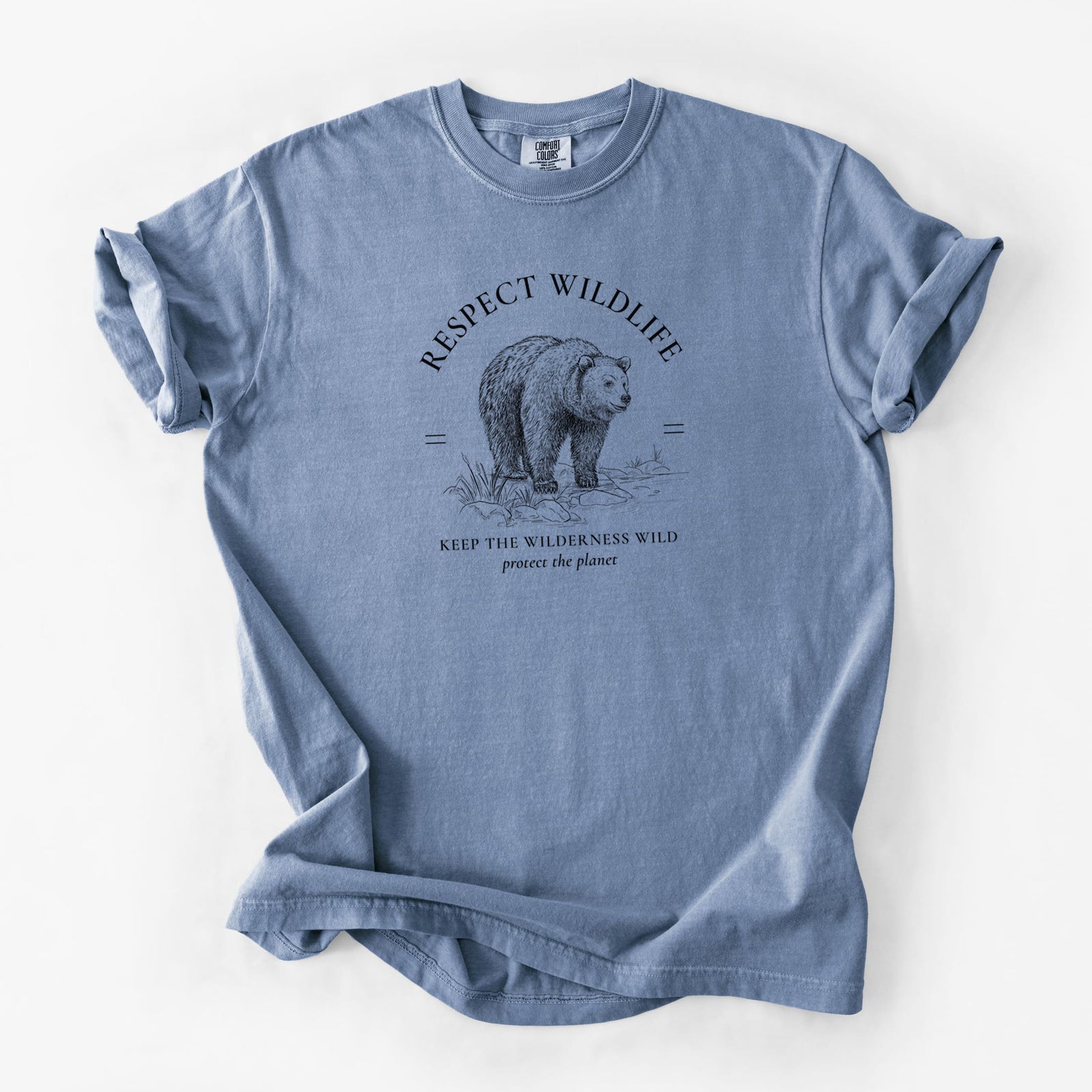 Blue jean Comfort Colors t-shirt laid flat, printed with a black ink bear framed by the words Respect Wildlife, Keep the Wilderness Wild.
