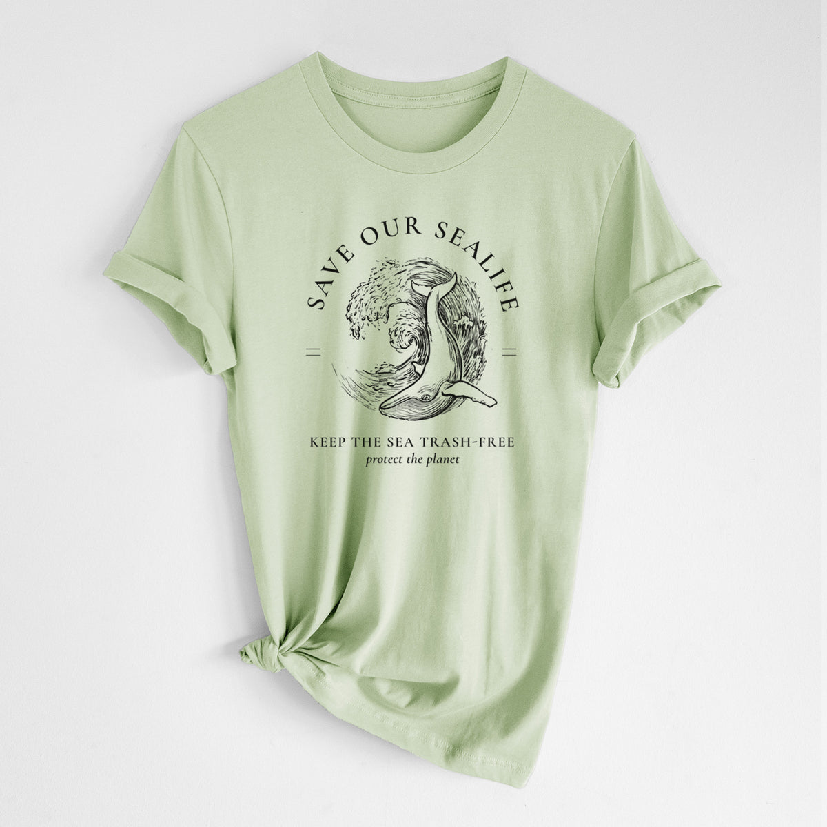 Spring green lightweight cotton t-shirt laid flat with the sleeves rolled, printed with a black ink whale in an ocean wave framed by the words Save Our Sealife, Keep the Sea Trash-Free.