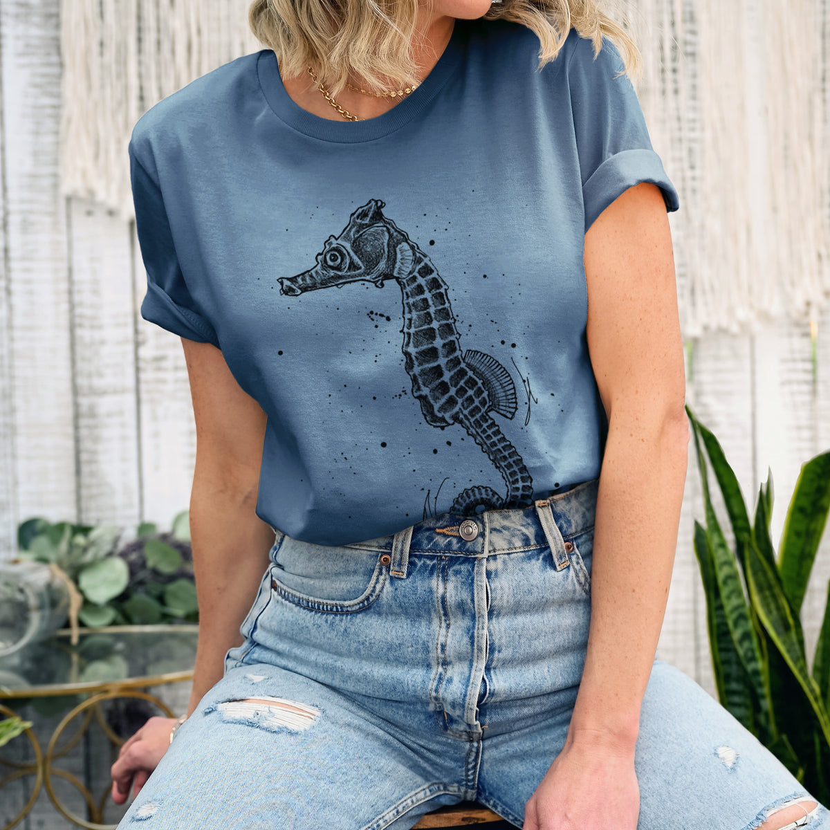 Woman wearing a steel blue lightweight cotton t-shirt printed with a detailed black ink illustration of a Pacific seahorse with its tail curled.
