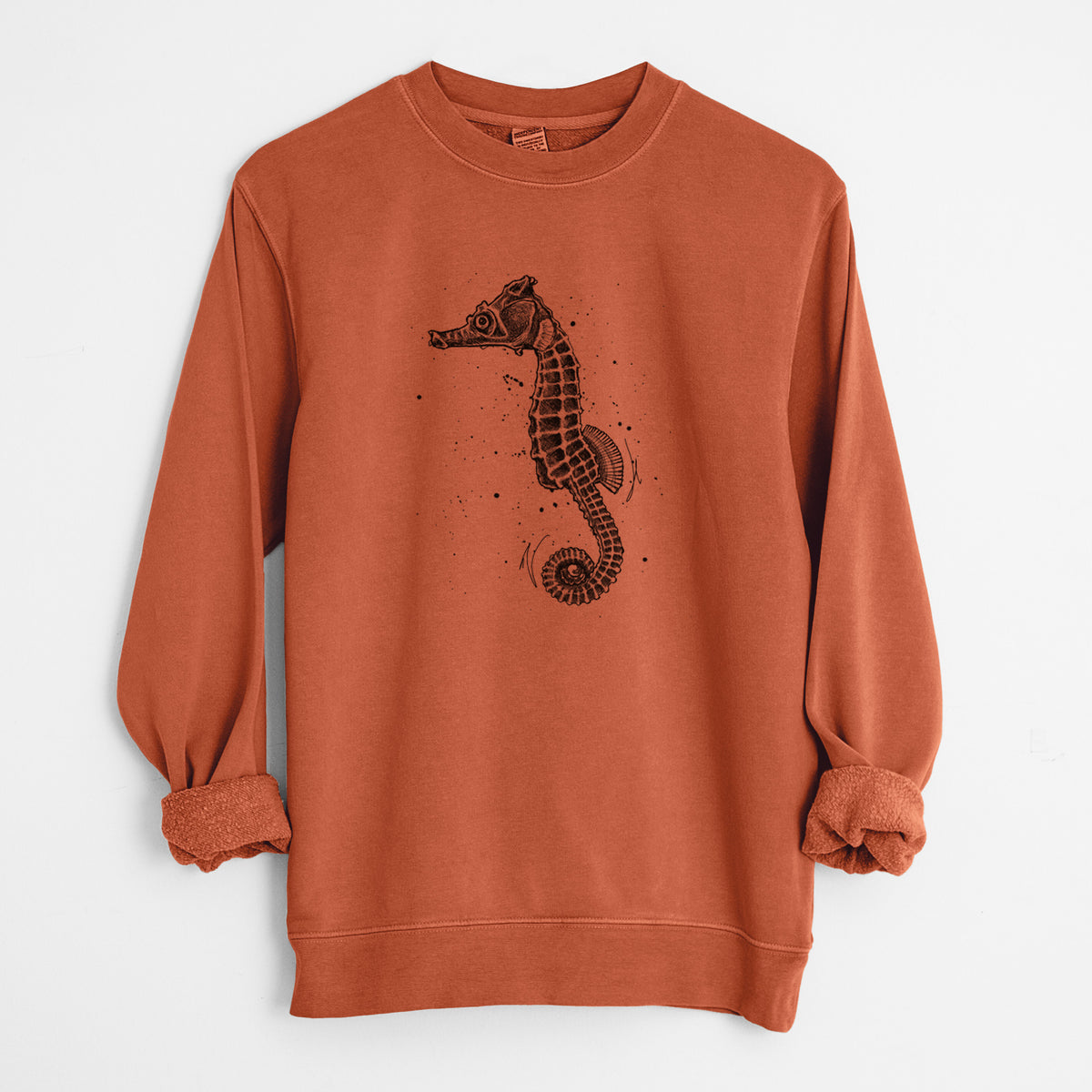 Amber orange pigment dyed crewneck sweatshirt laid flat with the sleeves rolled, printed with a detailed black ink illustration of a Pacific seahorse with its tail curled.