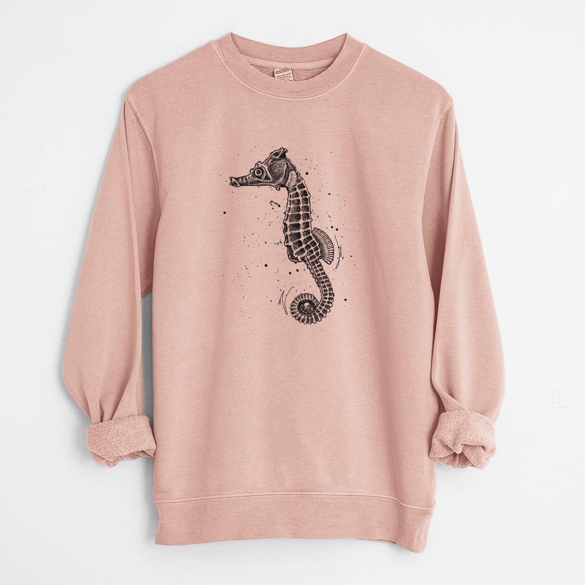 Dusty pink pigment dyed crewneck sweatshirt laid flat with the sleeves rolled, printed with a detailed black ink illustration of a Pacific seahorse with its tail curled.
