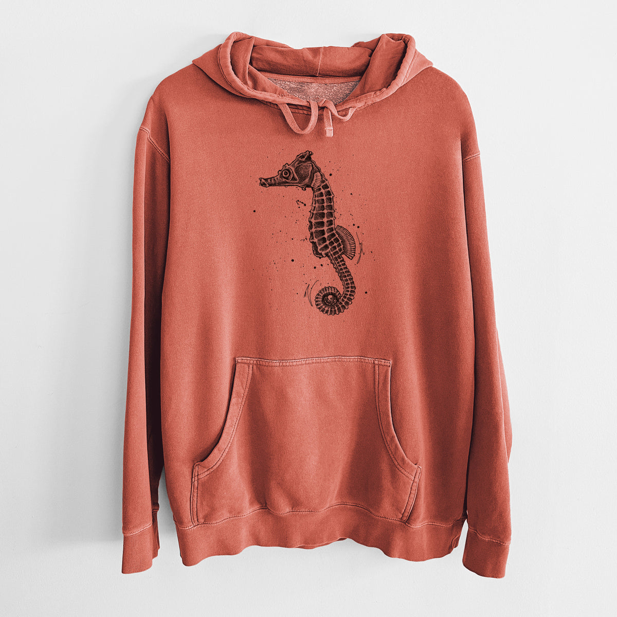 Amber orange pigment dyed hoodie laid flat, printed with a detailed black ink illustration of a Pacific seahorse with its tail curled.
