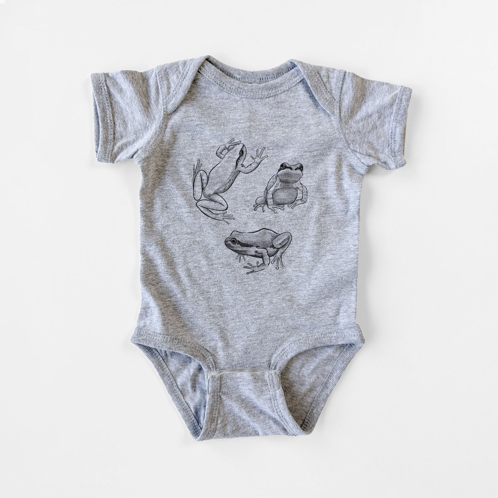 Grey baby bodysuit laid flat, printed with a black ink illustration of three Pacific tree frogs in different poses.