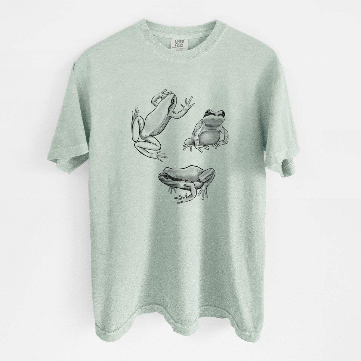 Bay green Comfort Colors t-shirt laid flat, printed with a black ink illustration of three Pacific tree frogs in different poses.