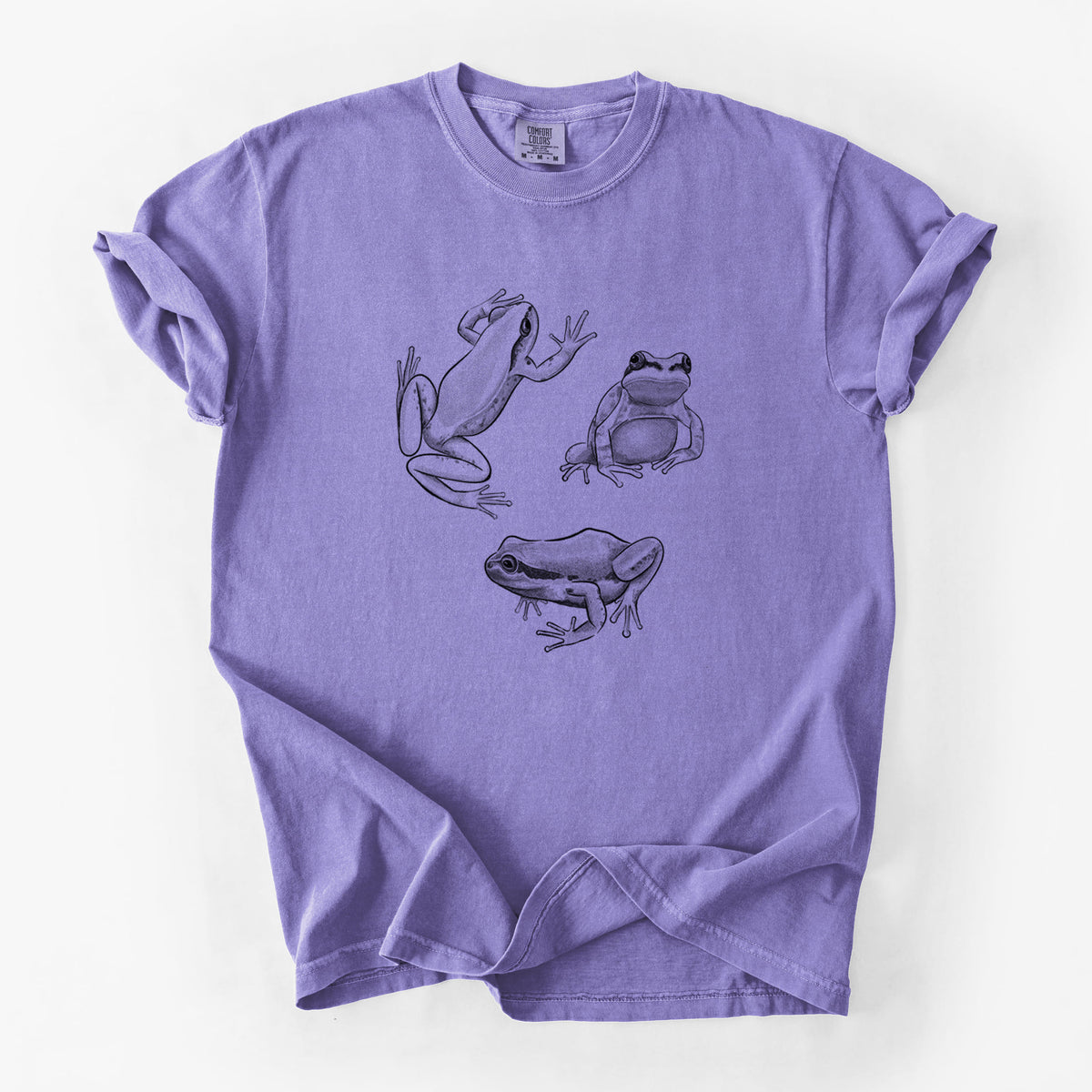 Violet purple Comfort Colors t-shirt laid flat, printed with a black ink illustration of three Pacific tree frogs in different poses.
