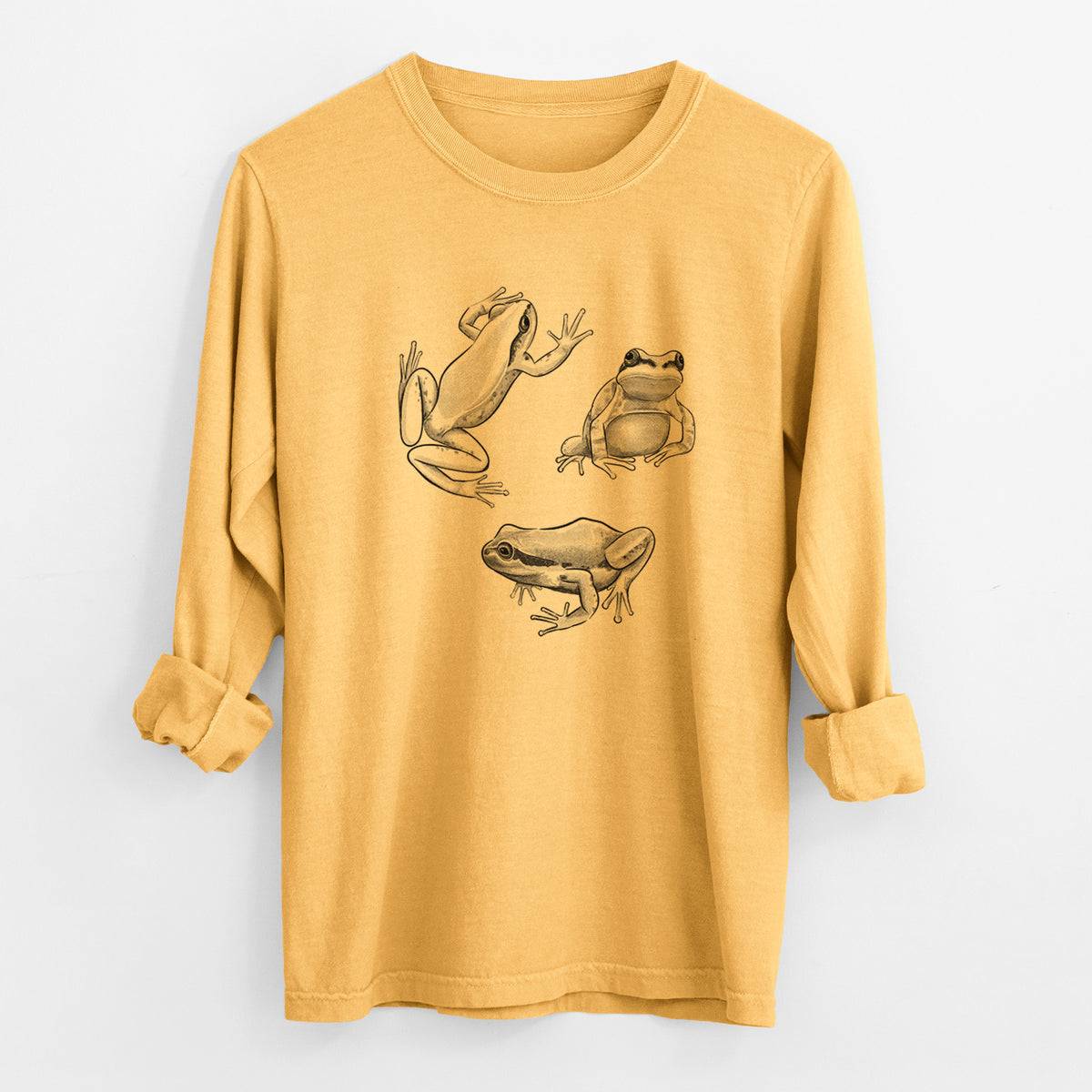 Golden wheat yellow Comfort Colors long sleeve shirt laid flat with the cuffs rolled, printed with a black ink illustration of three Pacific tree frogs in different poses.