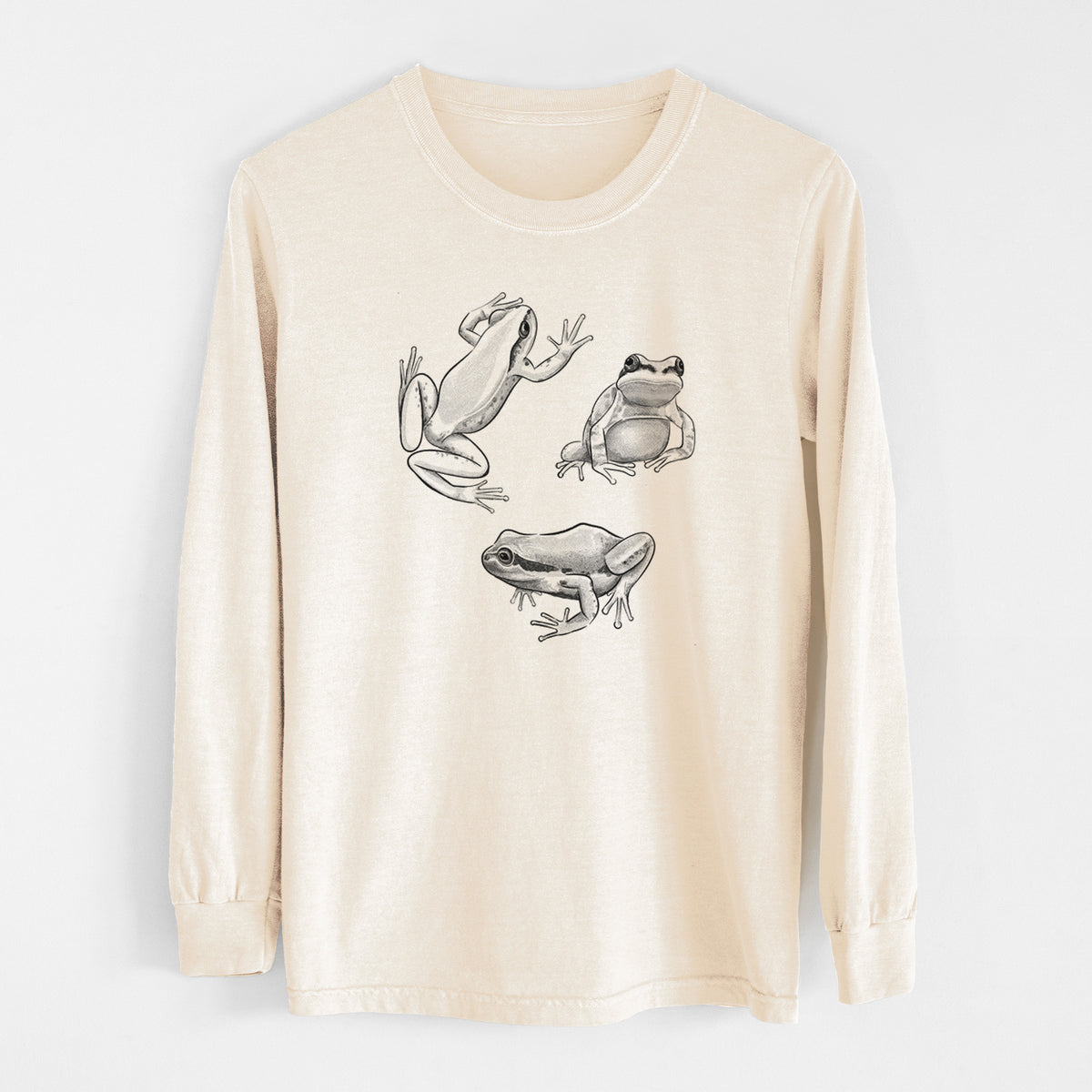 Ivory Comfort Colors long sleeve shirt laid flat, printed with a black ink illustration of three Pacific tree frogs in different poses.