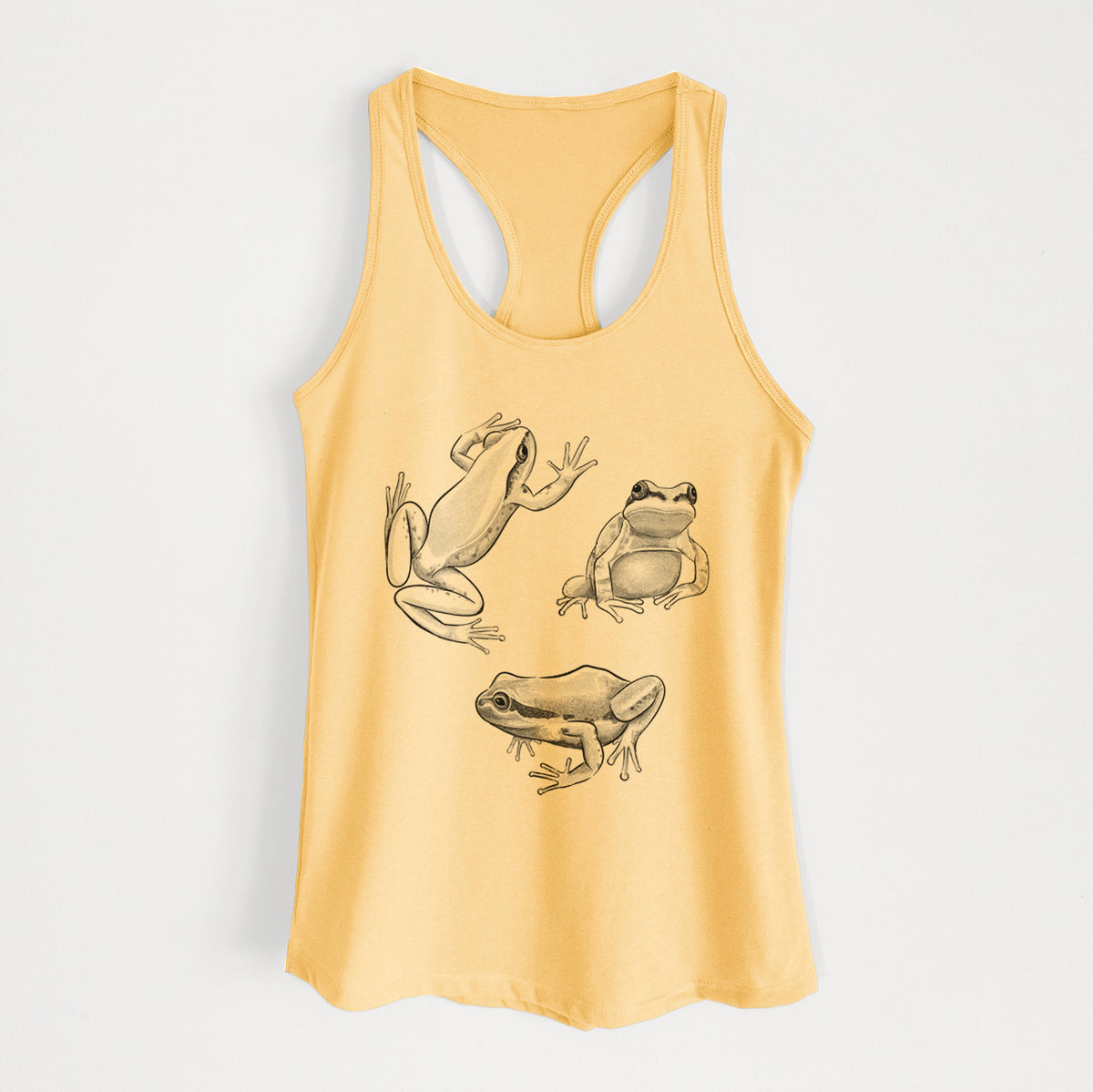 Banana cream women's racerback tank top laid flat, printed with a black ink illustration of three Pacific tree frogs in different poses.