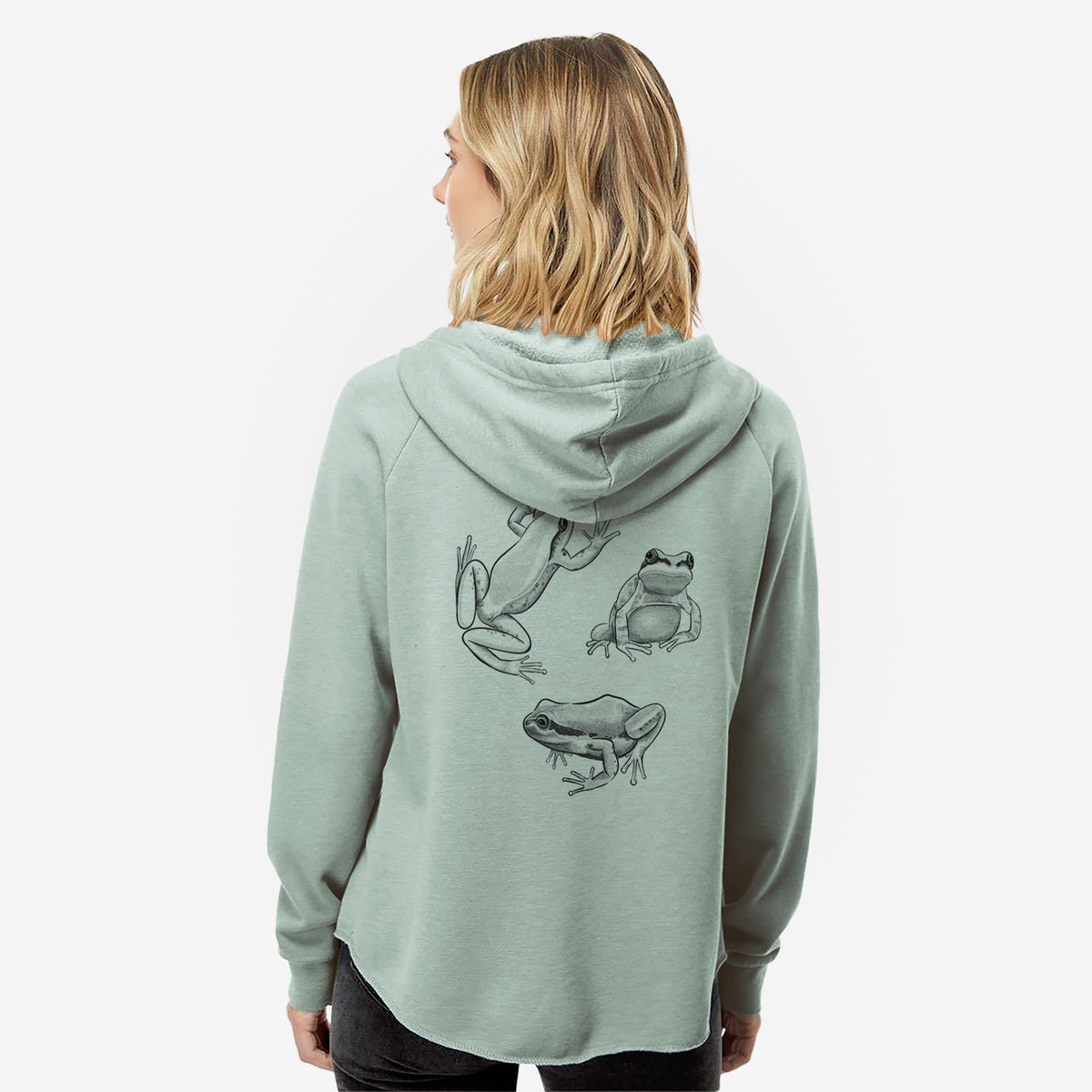 Woman wearing a sage green women's Cali Wave zip-up sweatshirt printed with a black ink illustration of three Pacific tree frogs in different poses, seen from behind.