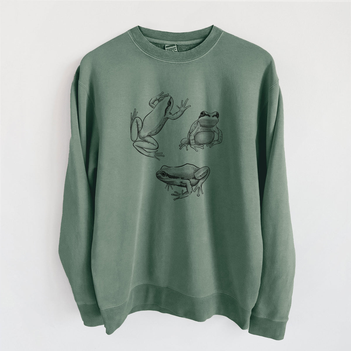 Alpine green pigment dyed crewneck sweatshirt laid flat, printed with a black ink illustration of three Pacific tree frogs in different poses.
