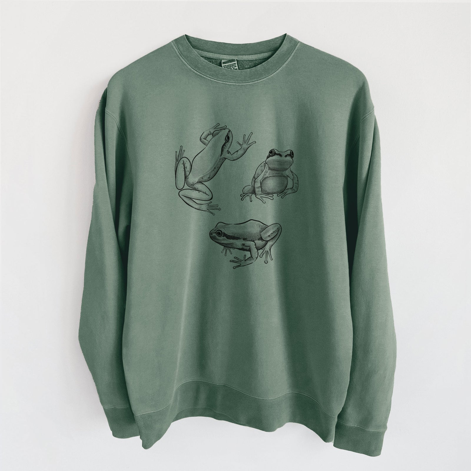Alpine green pigment dyed crewneck sweatshirt laid flat, printed with a black ink illustration of three Pacific tree frogs in different poses.