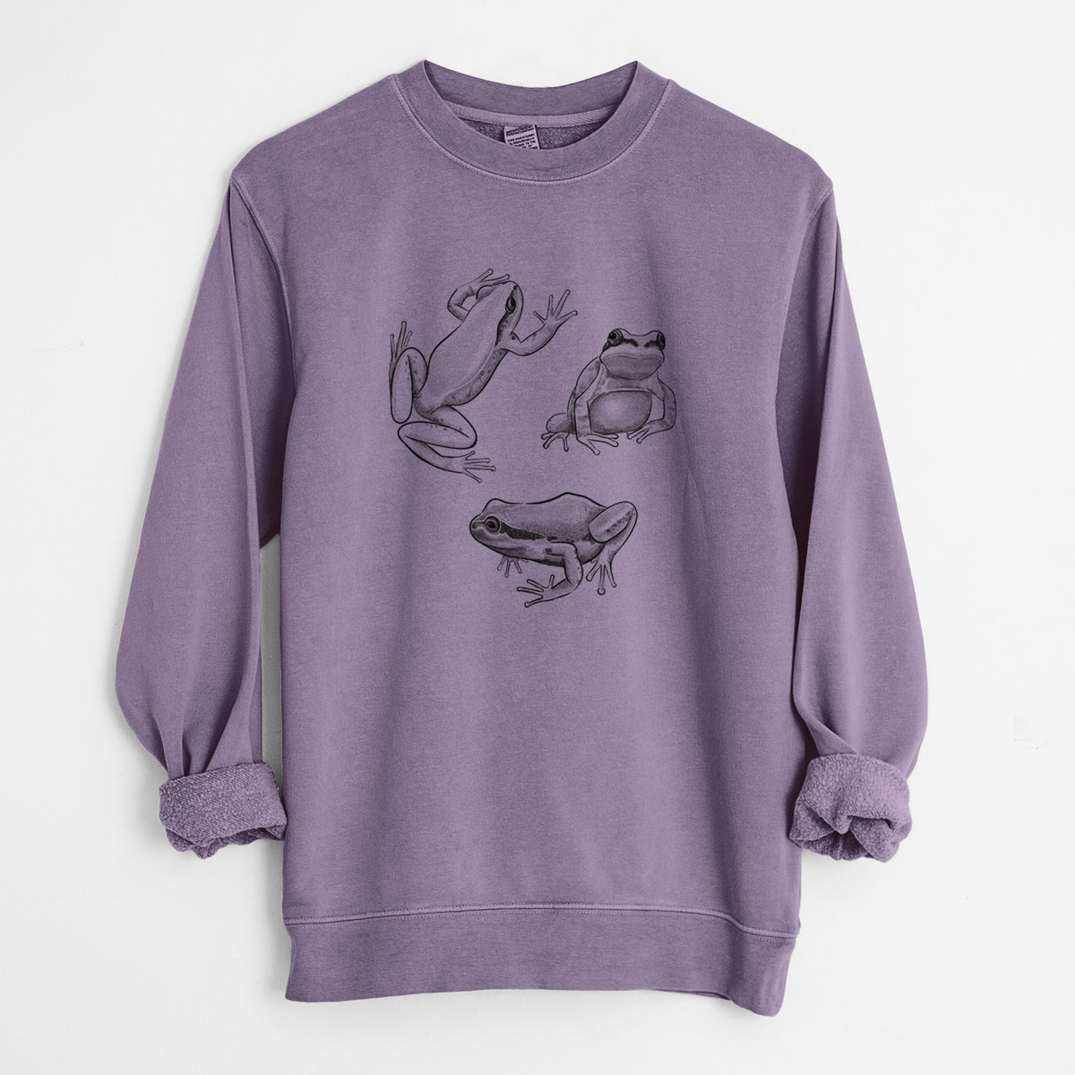 Plum purple pigment dyed crewneck sweatshirt laid flat with the sleeves rolled, printed with a black ink illustration of three Pacific tree frogs in different poses.