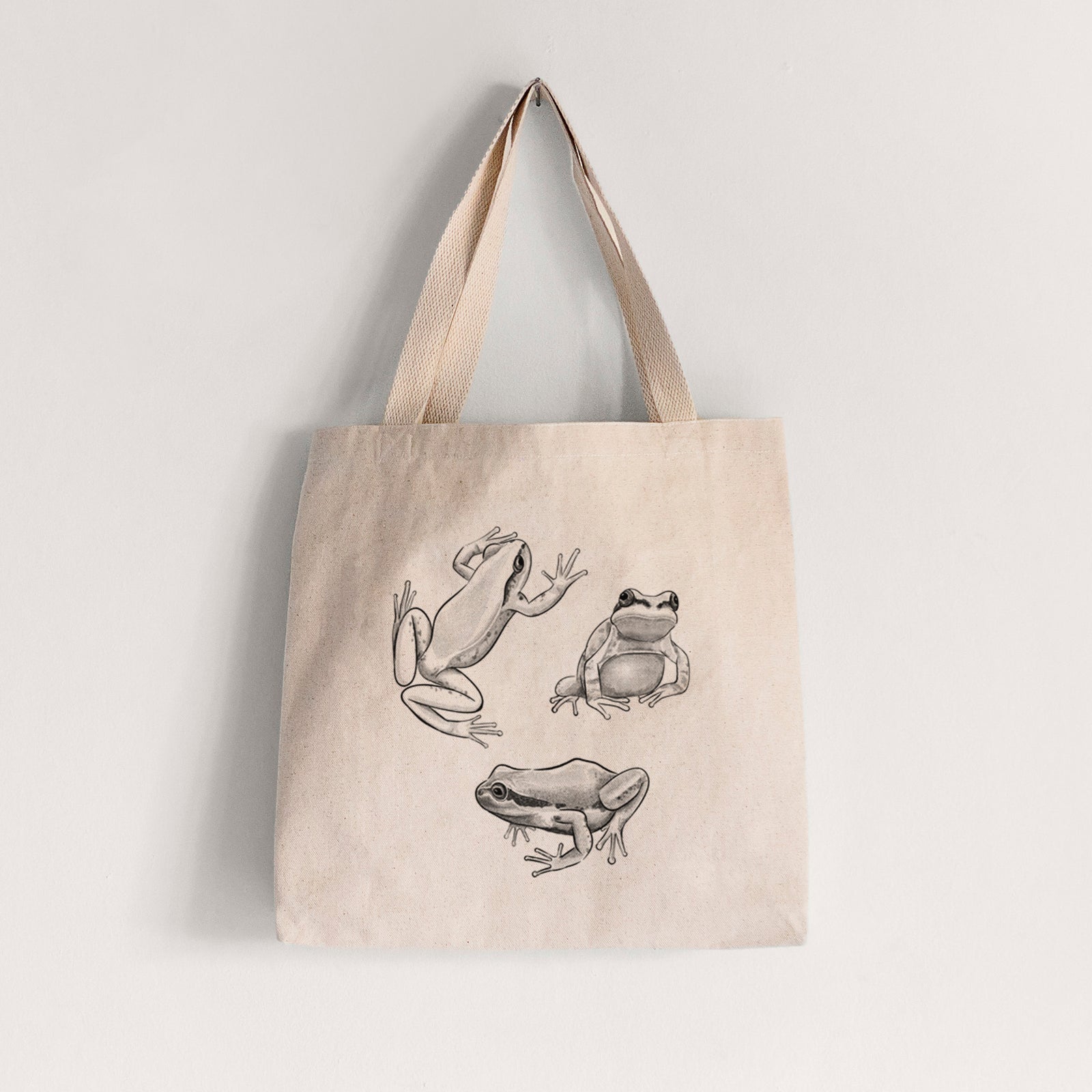 Natural canvas tote bag printed with a black ink illustration of three Pacific tree frogs in different poses.