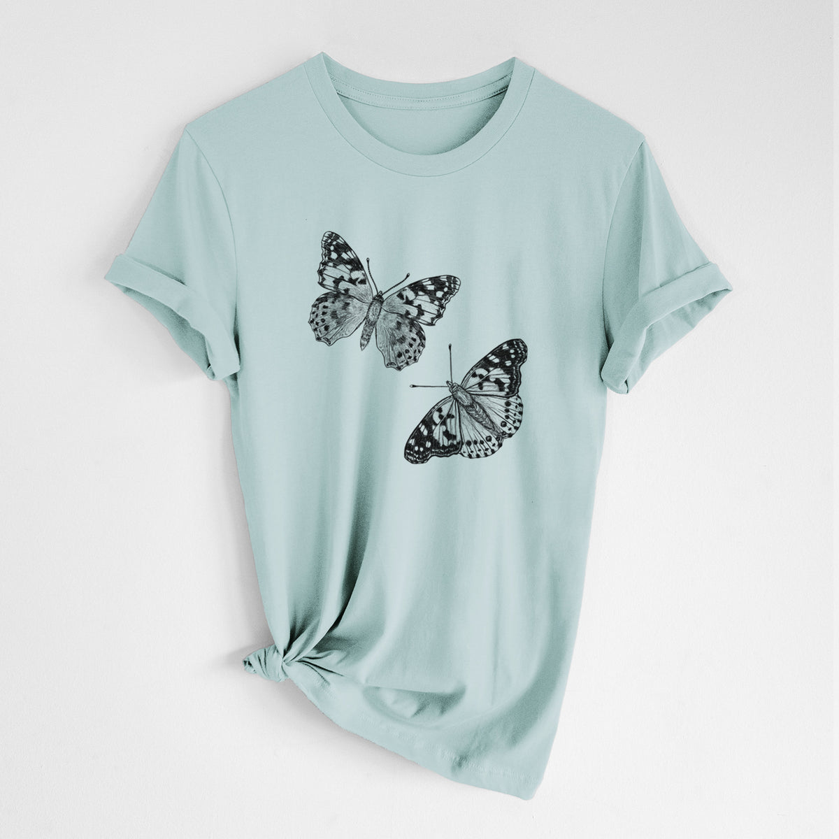 Dusty blue lightweight cotton t-shirt laid flat with the sleeves rolled, printed with a detailed black ink illustration of two painted lady butterflies.