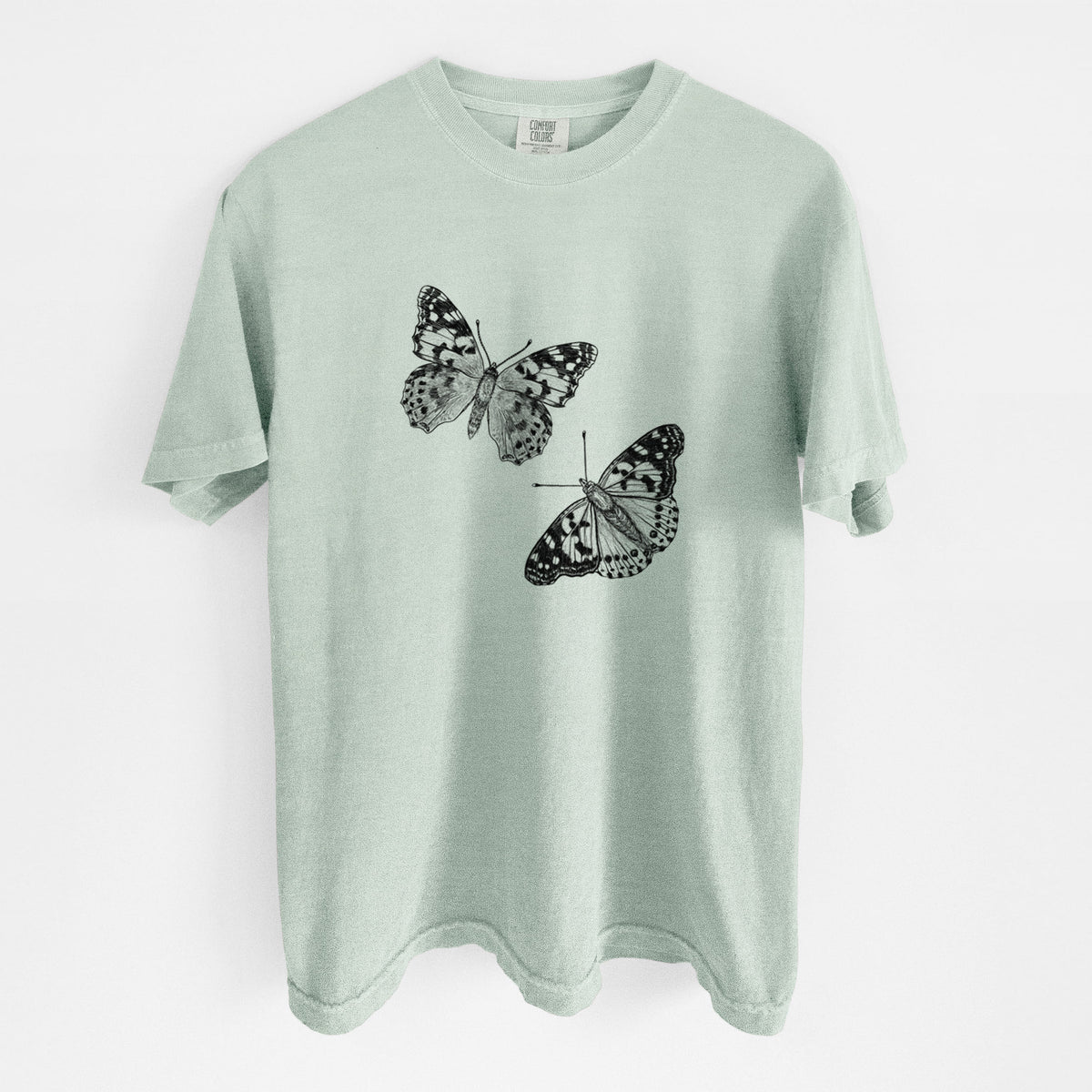 Bay green Comfort Colors t-shirt laid flat, printed with a detailed black ink illustration of two painted lady butterflies.