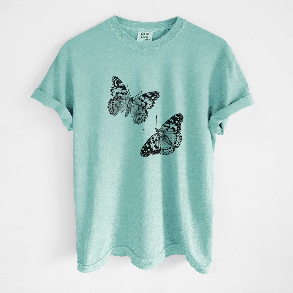 Chalky mint Comfort Colors t-shirt laid flat, printed with a detailed black ink illustration of two painted lady butterflies.