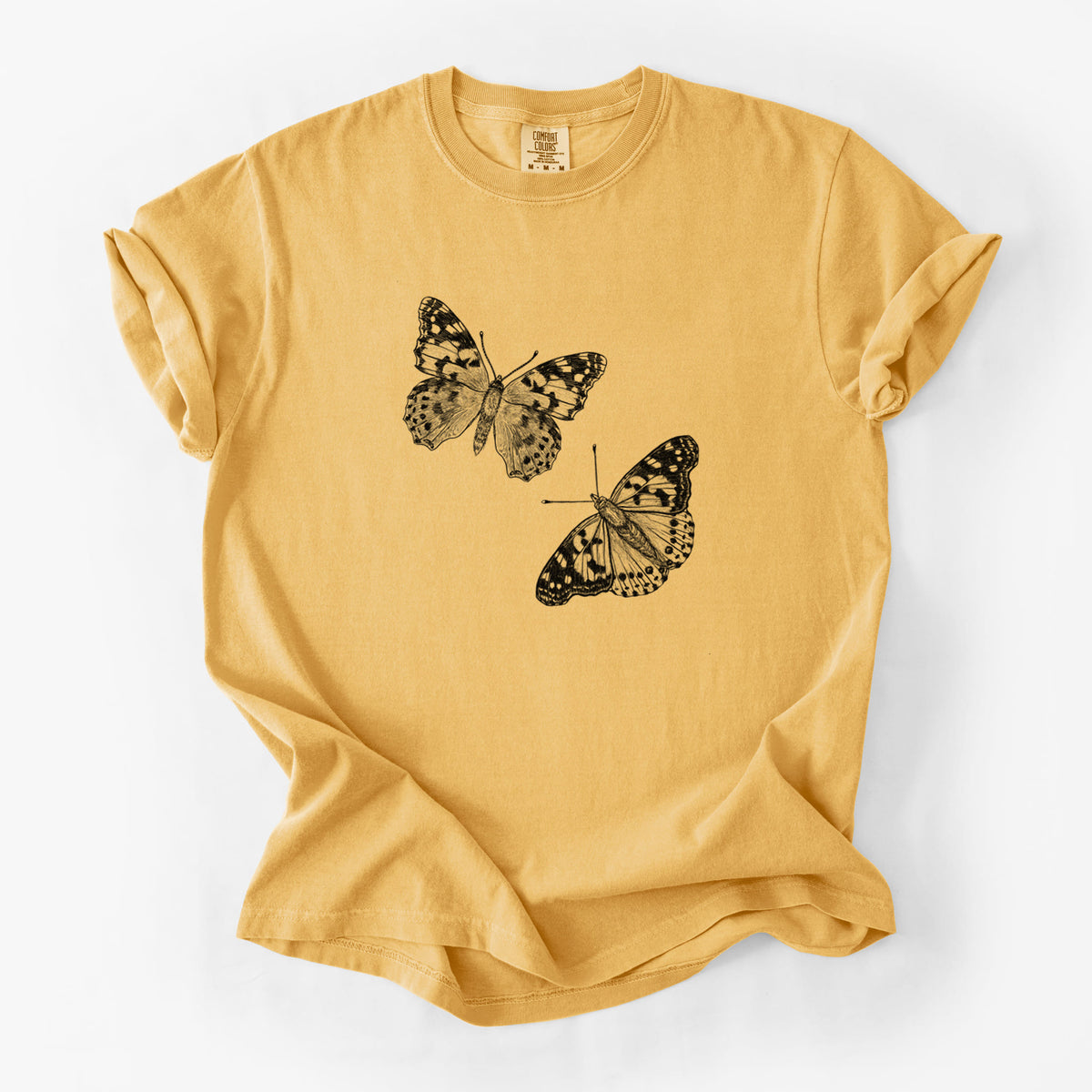 Golden wheat yellow Comfort Colors t-shirt laid flat, printed with a detailed black ink illustration of two painted lady butterflies.