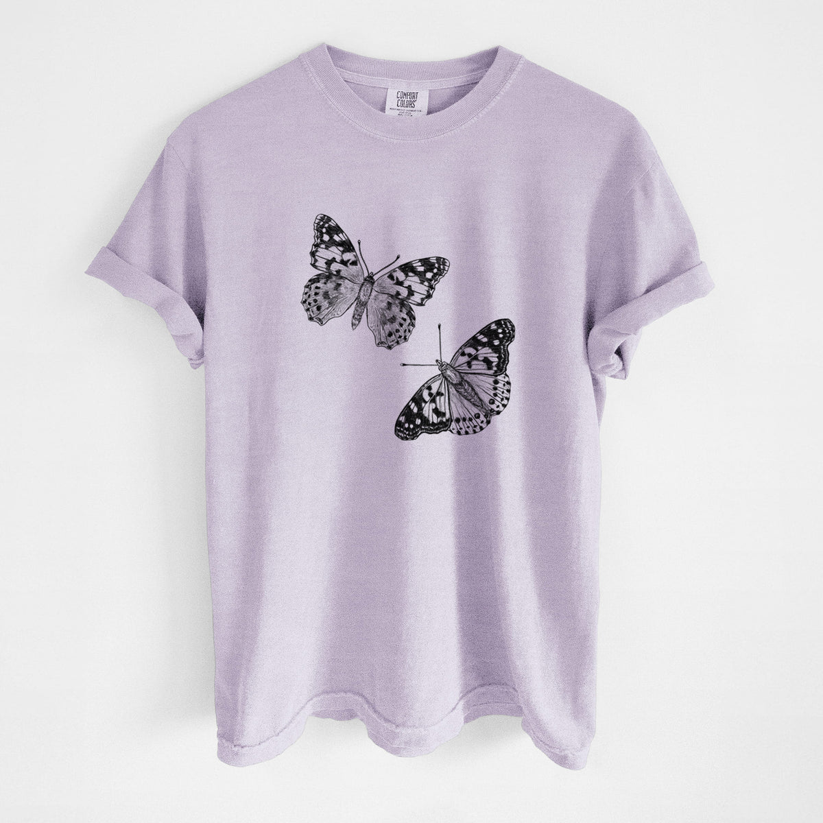 Orchid purple Comfort Colors t-shirt laid flat, printed with a detailed black ink illustration of two painted lady butterflies.