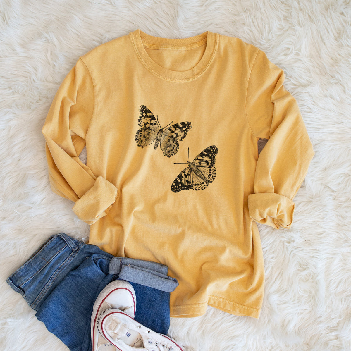 Golden wheat yellow Comfort Colors long sleeve shirt printed with a detailed black ink illustration of two painted lady butterflies, shown in a lifestyle photo.