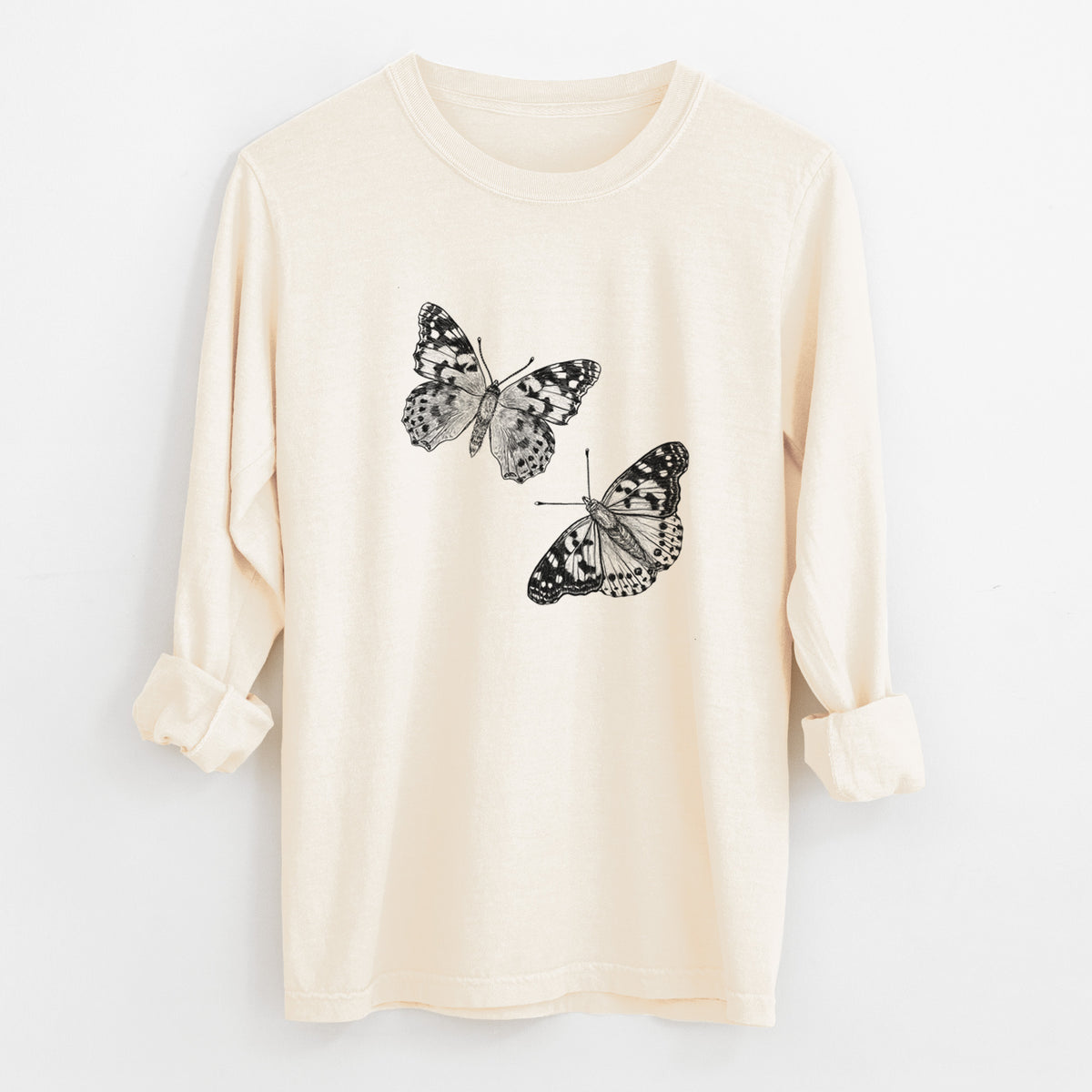 Ivory Comfort Colors long sleeve shirt laid flat with the cuffs rolled, printed with a detailed black ink illustration of two painted lady butterflies.
