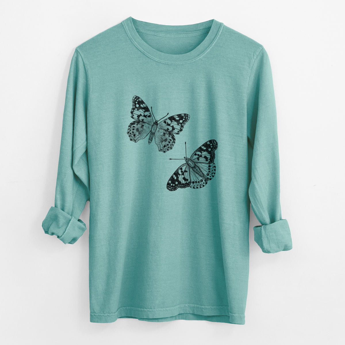 Reef green Comfort Colors long sleeve shirt laid flat with the cuffs rolled, printed with a detailed black ink illustration of two painted lady butterflies.