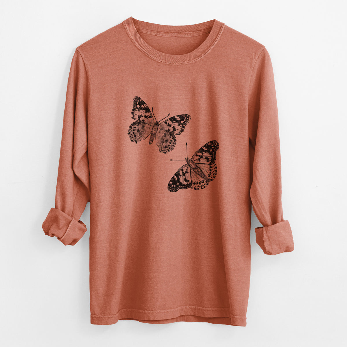 Yam burnt orange Comfort Colors long sleeve shirt laid flat with the cuffs rolled, printed with a detailed black ink illustration of two painted lady butterflies.
