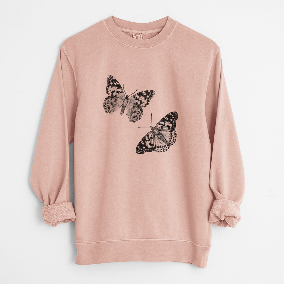 Dusty pink pigment dyed crewneck sweatshirt laid flat with the sleeves rolled, printed with a detailed black ink illustration of two painted lady butterflies.