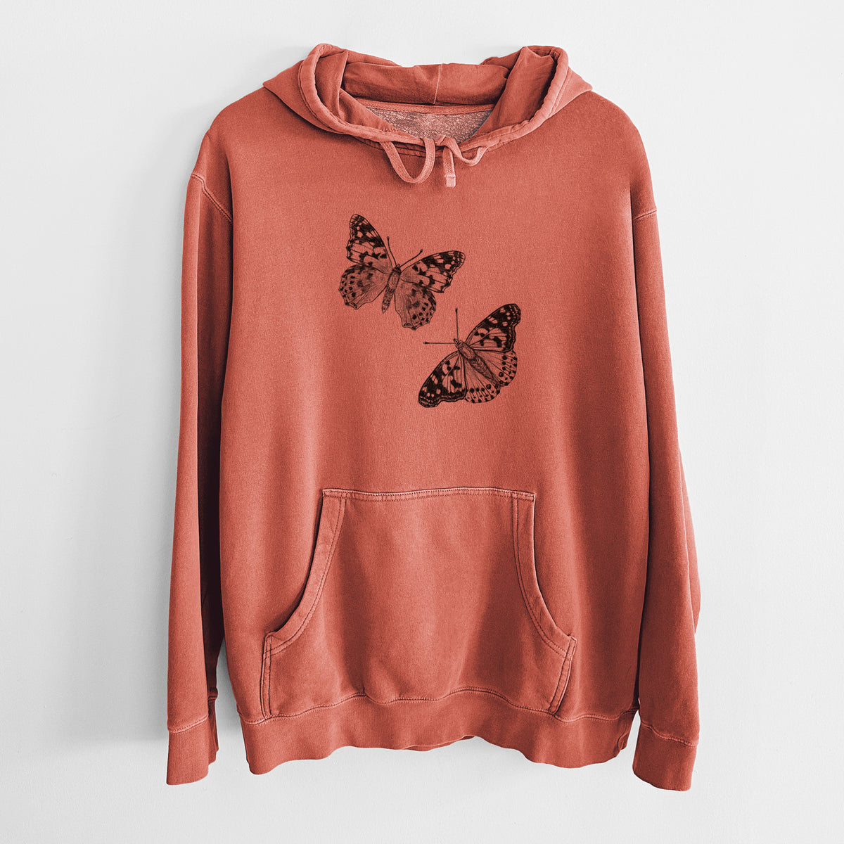 Amber orange pigment dyed hoodie laid flat, printed with a detailed black ink illustration of two painted lady butterflies.